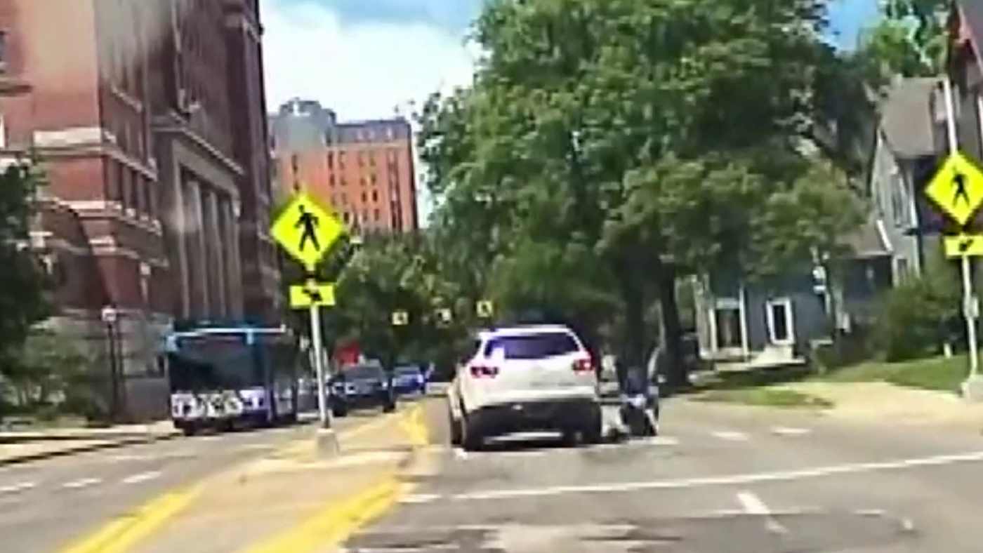 Dash cam still from Ann Arbor hit-and-run footage showing a white Chevrolet Traverse at a marked crosswalk