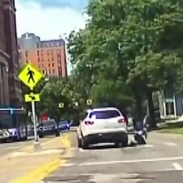 Dash cam still from Ann Arbor hit-and-run footage showing a white Chevrolet Traverse at a marked crosswalk