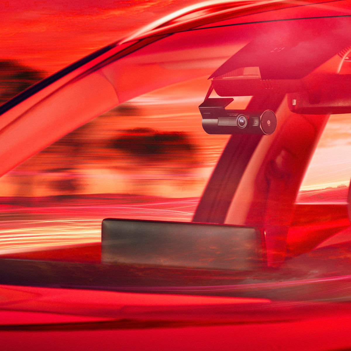 BlackVue front camera mounted behind a windshield in warm red light