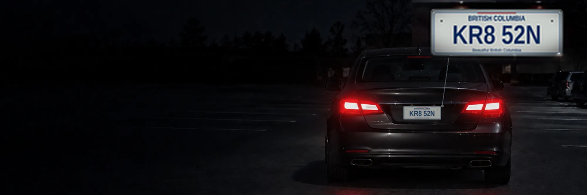 A car at night in a dark parking lot with a magnified licence plate